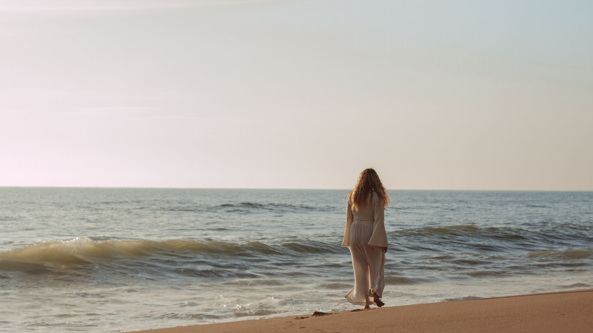 Malin blickt an einem Strand in der Abendsonne aufs Meer hinaus